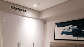 Een moderne slaapkamer met een groot bed, een kledingkast en een schilderij aan de muur.