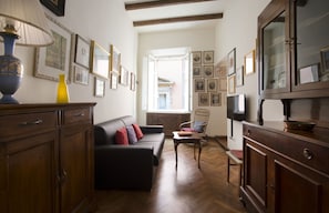 A living room with a sofa, a chair, a lamp, and a cabinet. - UR-NEST Clavature - Piazza Maggiore Collection (Bologna)