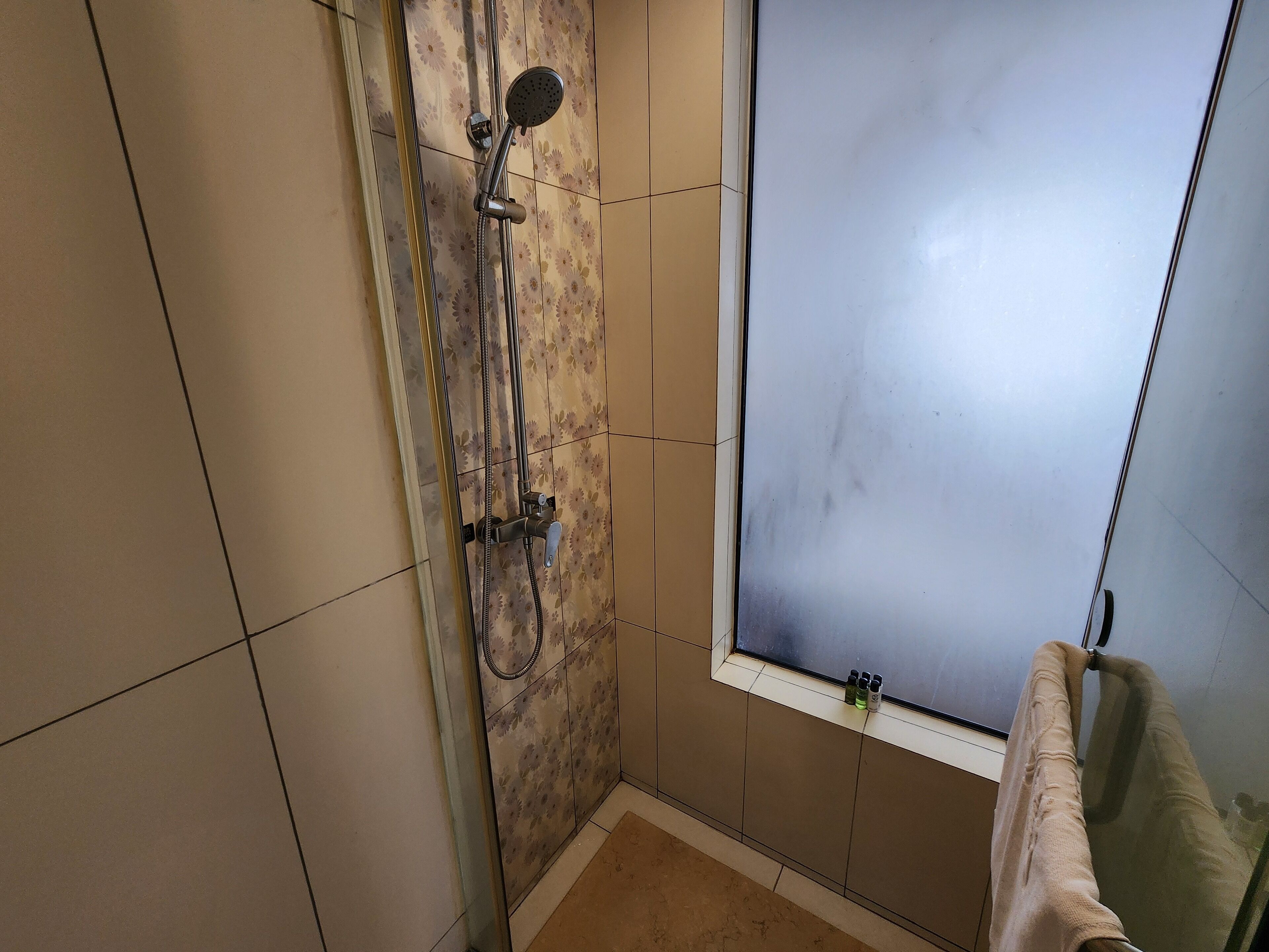 A shower with a handheld showerhead and a handheld shower attachment.