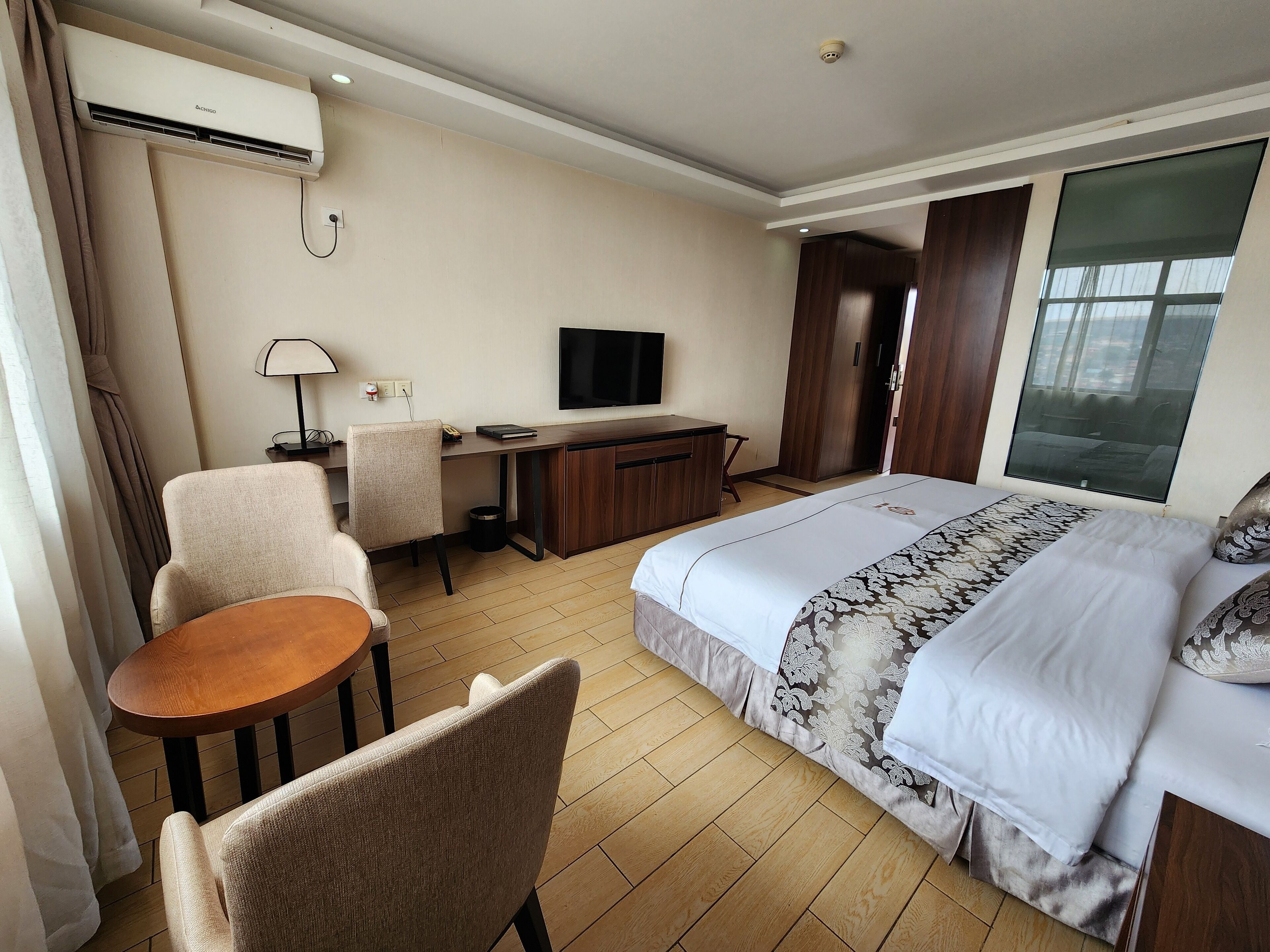 Une chambre d’hôtel comprenant un lit, un bureau avec une chaise, une télévision et une fenêtre.