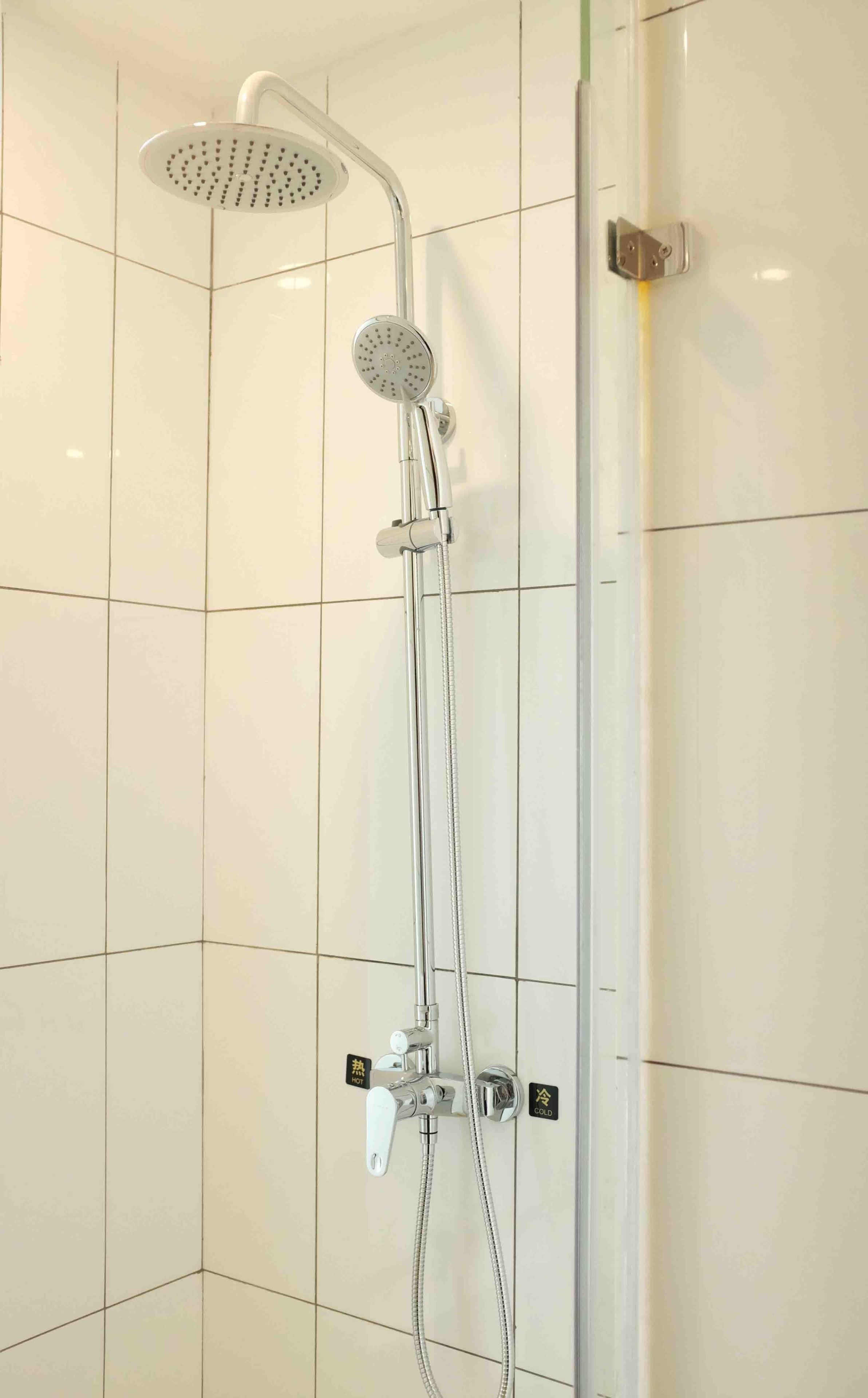 A shower with a handheld showerhead and a fixed overhead showerhead, both with multiple nozzles.
