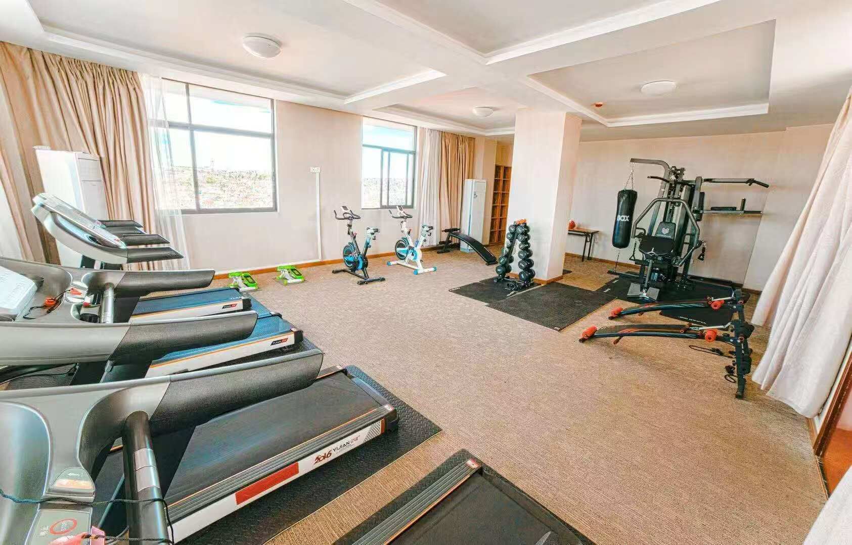 Un gimnasio con cintas de correr, bicicletas estáticas y equipo de pesas.