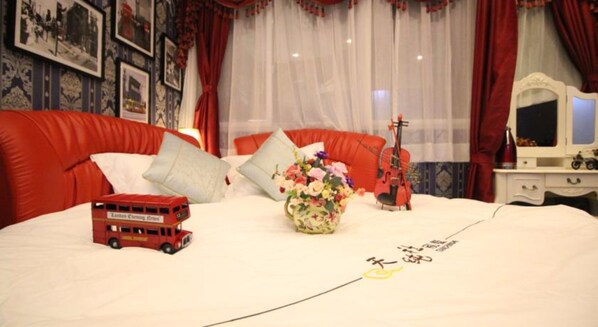 A neatly made bed with a red double-decker bus, a floral vase, and a violin on the bed. - Xiamen Feisu Tianchunshe Holiday Villa (Xiamen)