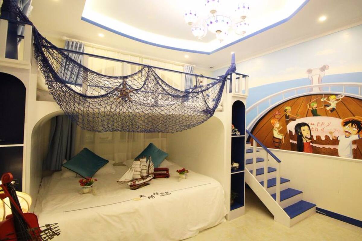 A child's bedroom with a bunk bed, a net canopy, a mural of a boat, and a staircase.