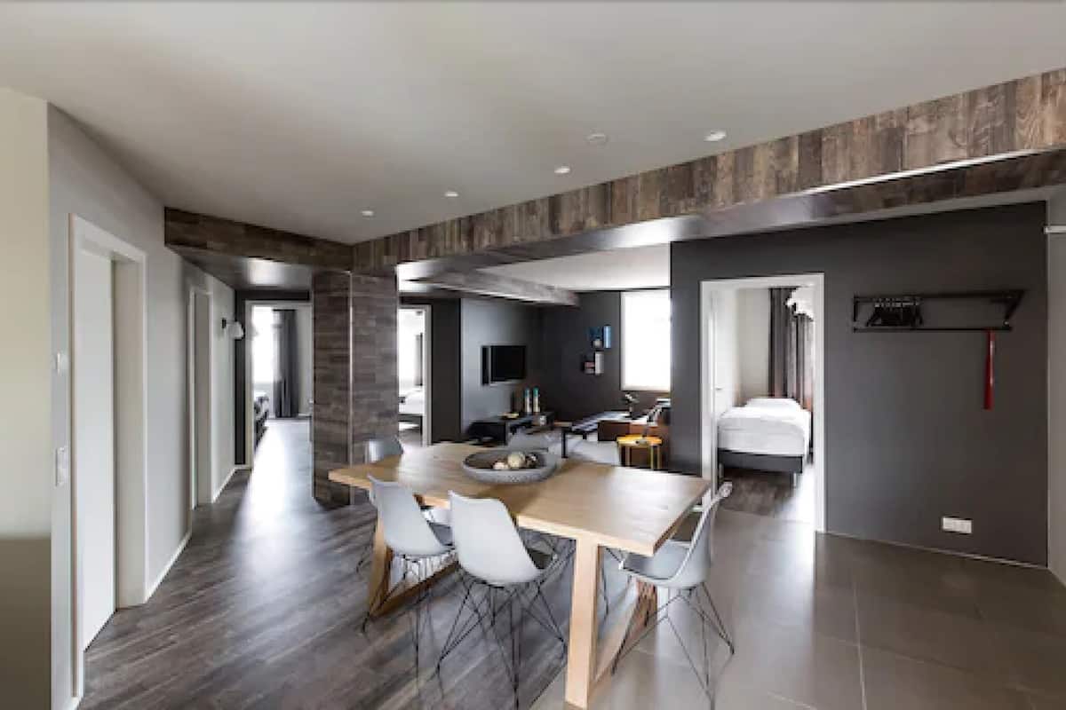 A modern interior with a dining area, kitchen, and a bedroom.