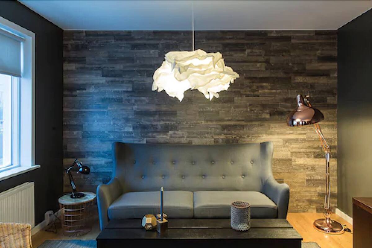 A modern living room with a grey sofa, a round coffee table, a hanging light fixture, and a floor lamp.