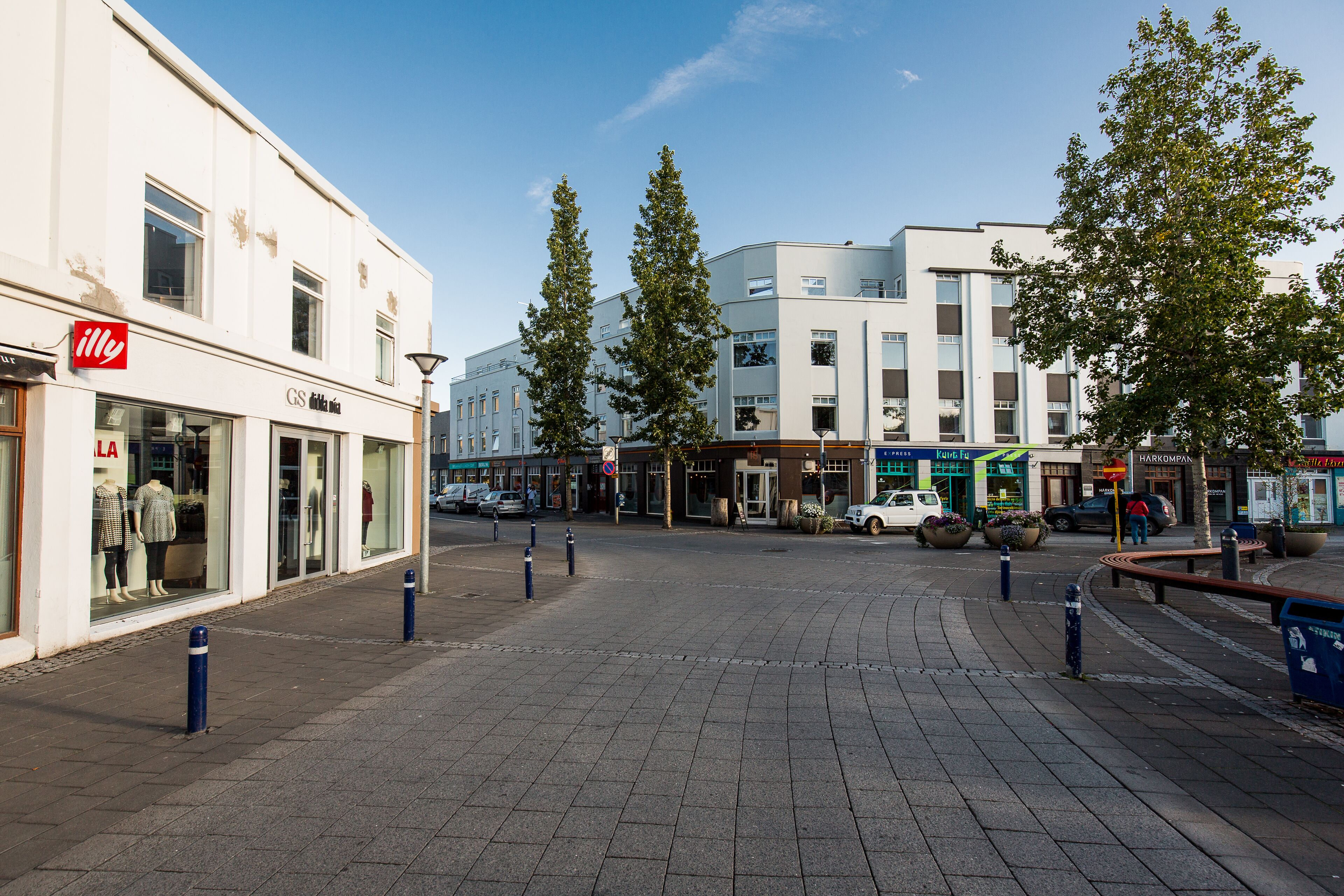 A pedestrian street with storefronts, including a visible 'elle' store, and a modern building with signage.