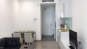 Ein kompakter Wohnraum mit Essbereich, einer Couch, einem Fernseher und einer Küchenzeile.