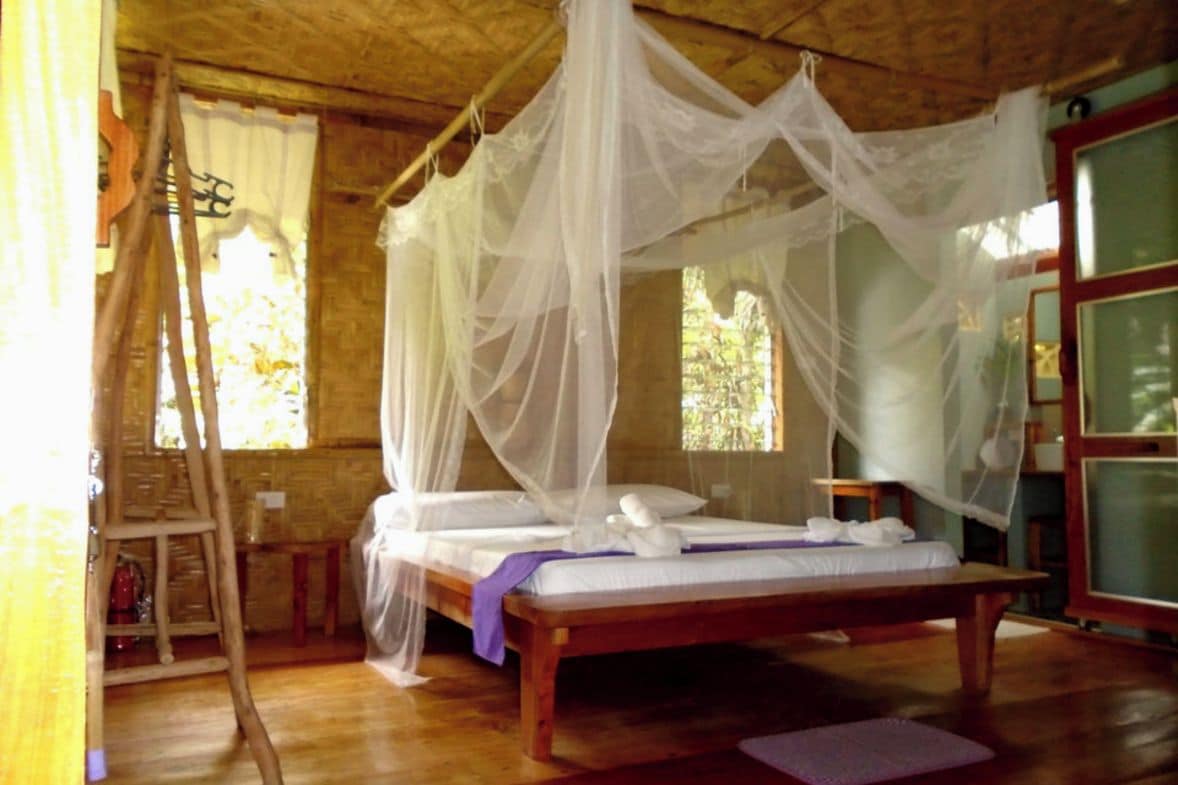 A room with a wooden bed, white canopy, and a wooden ladder.