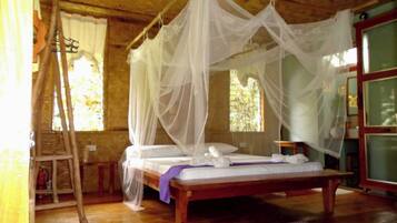 A room with a wooden bed, white canopy, and a wooden ladder.