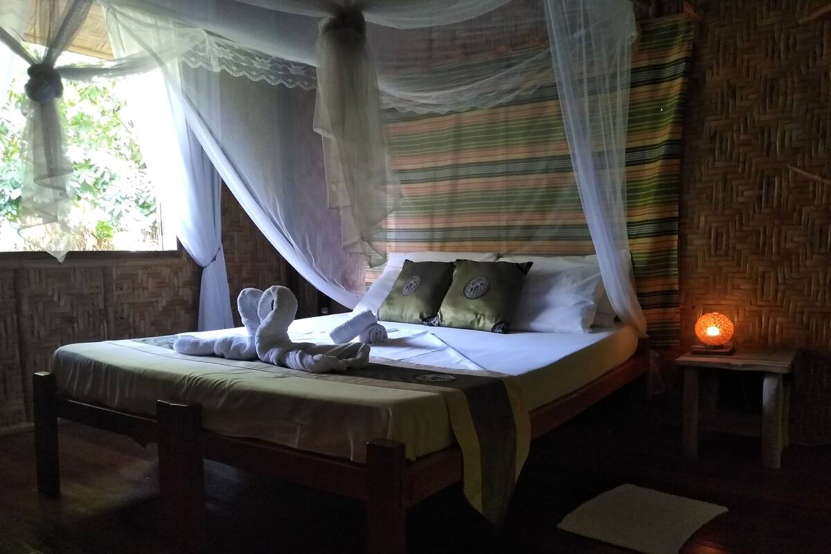 A bed with a canopy, pillows, and a bedside table with a lamp.
