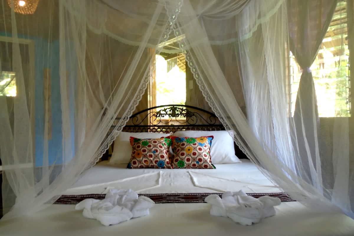A bed with a canopy, pillows, and a neatly made bedspread.