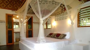 A bedroom with a canopy bed, a small bedside table, and a nightstand. - Nypa Style Resort Camiguin (Mambajao)