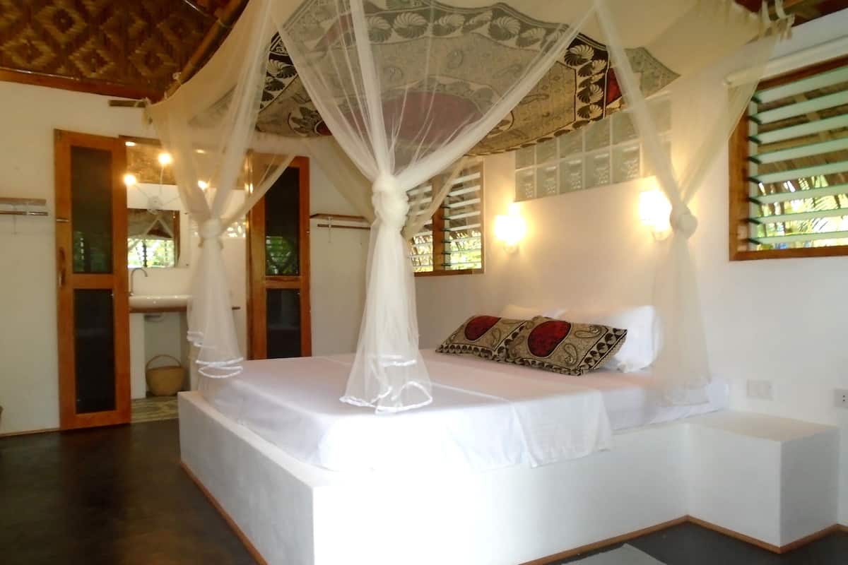 A bedroom with a canopy bed, a small bedside table, and a nightstand.