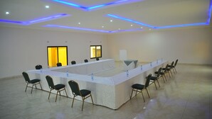 Uma sala de conferência com uma mesa comprida, cadeiras e um quadro branco.