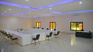 Uma sala de conferências com uma mesa comprida, cadeiras e uma mesa de recepção.