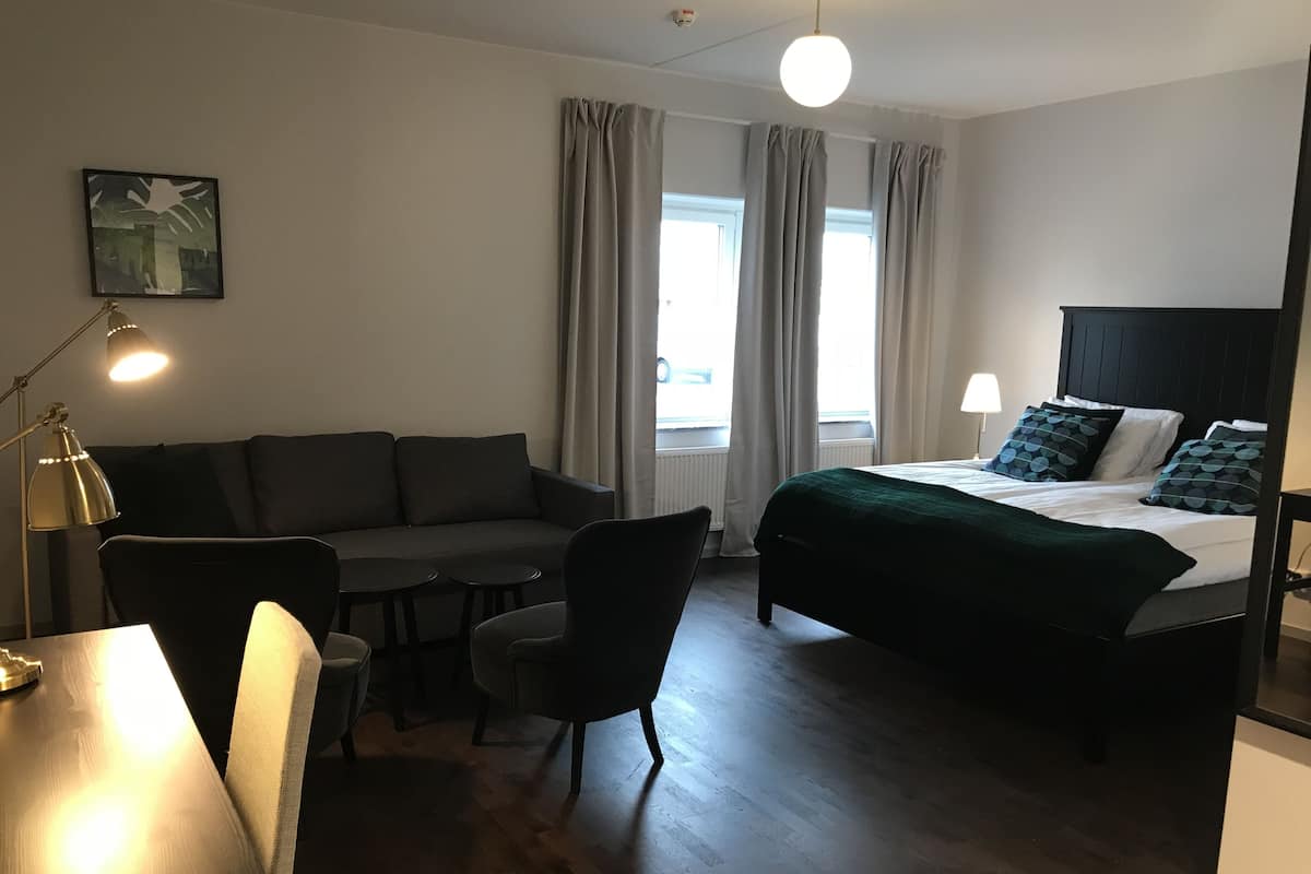 Quarto de hotel moderno com cama, sofá, escrivaninha e cadeira.