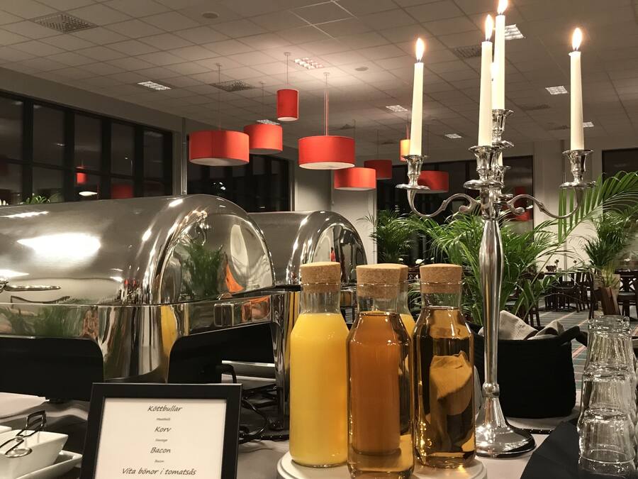 A buffet table with a menu, bottles of beverages, and a candle centerpiece.