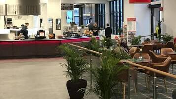 A spacious indoor area with a reception desk, seating area, and potted plants.