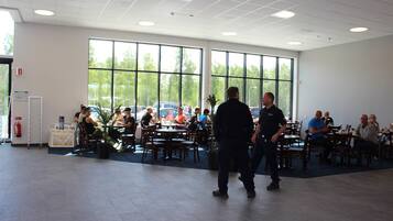 A spacious indoor dining area with large windows, multiple tables, and chairs.