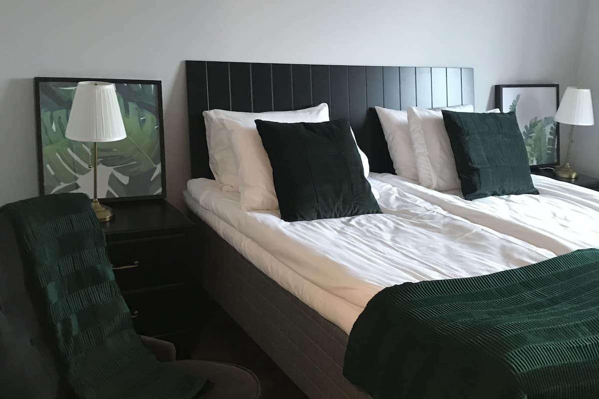 Quarto de hotel com uma cama, duas mesas de cabeceira, uma cadeira e um abajur.