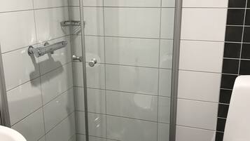 A bathroom with a glass-enclosed shower, a white sink, and a toilet.