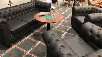 A modern lounge area with a plaid carpet, leather sofas, and a round wooden coffee table.
