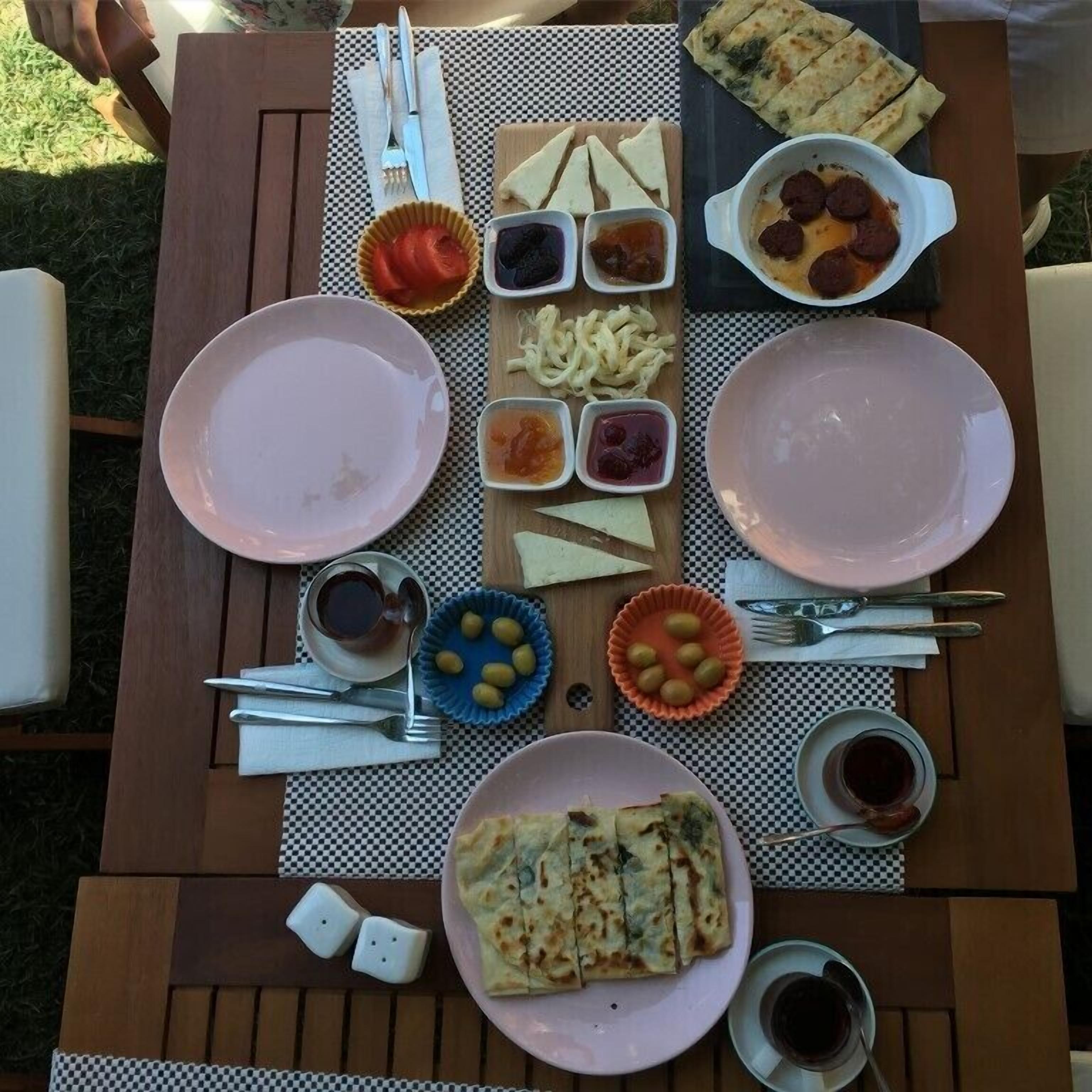 A table set for a meal with various dishes, including flatbreads, a salad, and a bowl of soup.