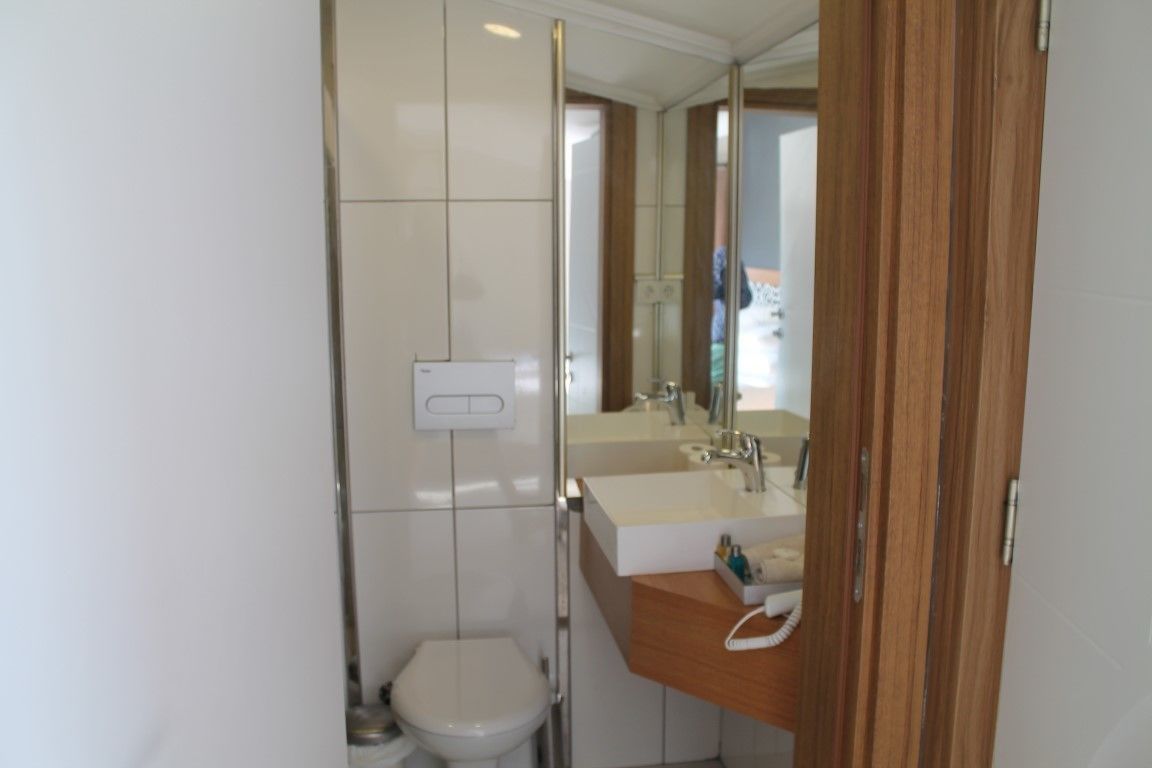 Casa de banho moderna com sanita, lavatório e espelho.