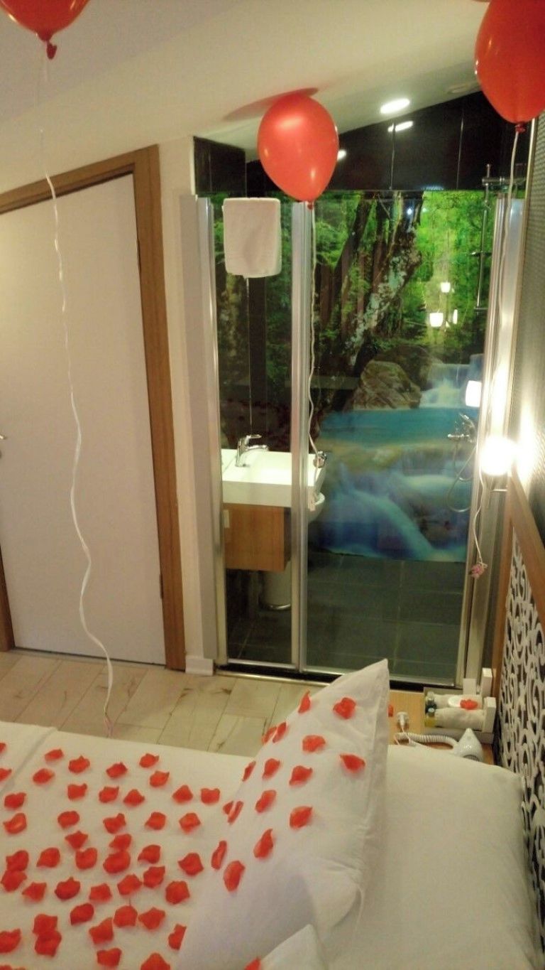 Une chambre d’hôtel avec un lit, une porte vitrée donnant sur une salle de bain et une vue sur une cascade.