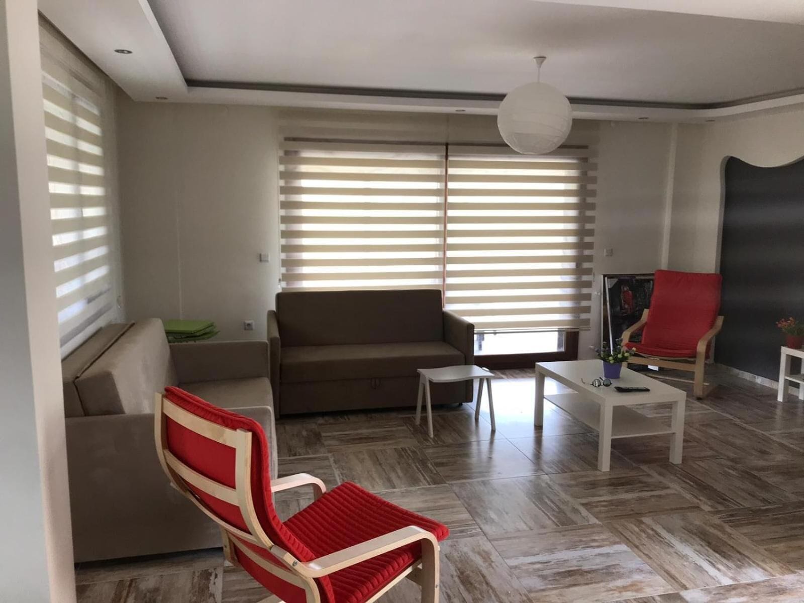 A modern living room with a sofa, a red chair, a coffee table, and a television.