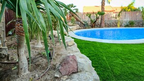 A backyard with a swimming pool, green grass, and palm trees. - Villa Yotam (Eilat)