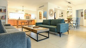 A modern living room with a sofa, coffee table, and dining area. - Villa Yotam (Eilat)