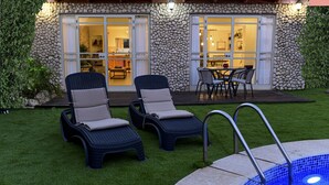 A pool area with two lounge chairs and a stone wall. - Villa Yotam (Eilat)
