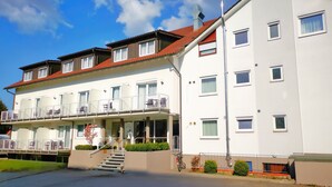 A multi-story hotel with balconies, a covered entrance, and a clear sky. - Hotel Löwen (Meckenbeuren)