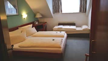 A hotel room with two beds, a nightstand, a lamp, and a window with curtains.