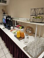 Disposição de buffet com máquina de café, diversas bebidas e copos.