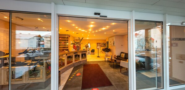 Vestíbulo de hotel con mostrador de recepción, zona de estar y chimenea.