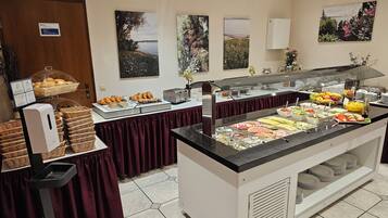 Un espace buffet proposant différents plats, un coin où l’on peut se servir soi-même, et un ventilateur de plafond.