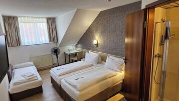 Una camera d'albergo con un letto, una scrivania, una sedia, un armadio e un box doccia.