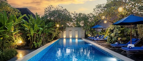 Una piscina al aire libre, sombrillas, sillones reclinables de piscina