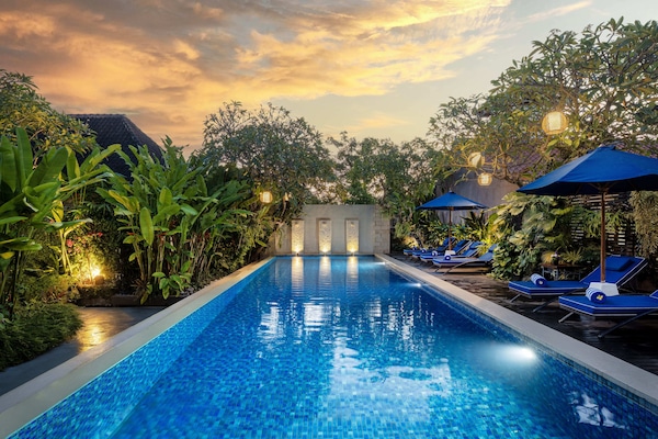 Una piscina al aire libre, sombrillas, sillones reclinables de piscina