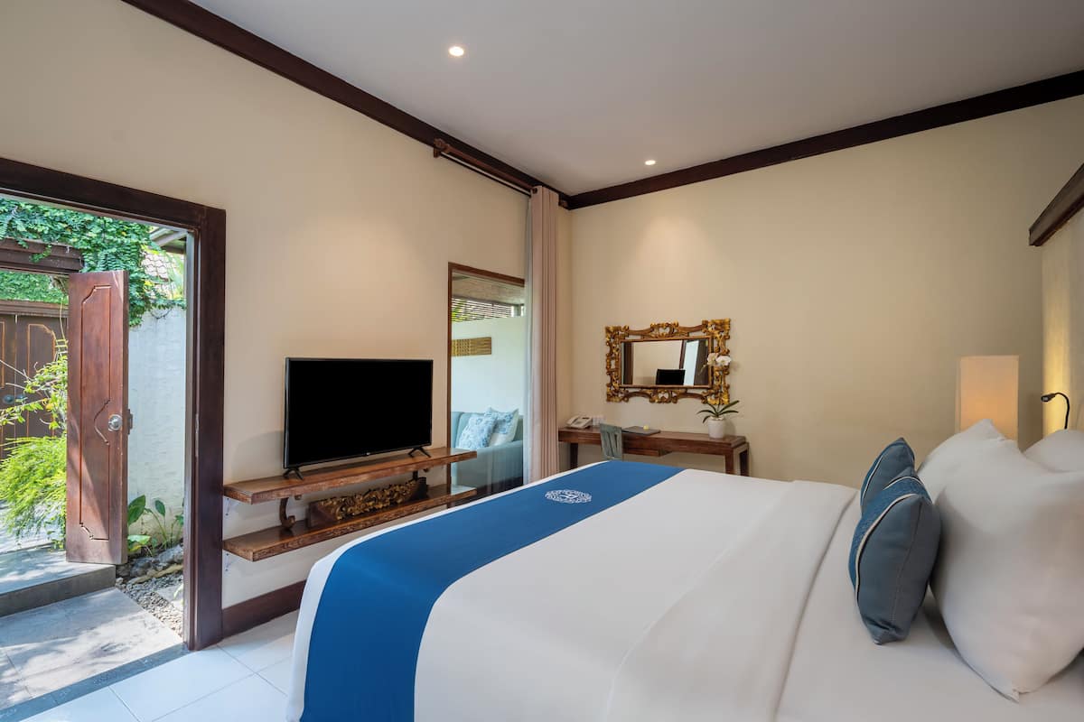 A hotel room with a bed, a television, a desk, and a mirror.