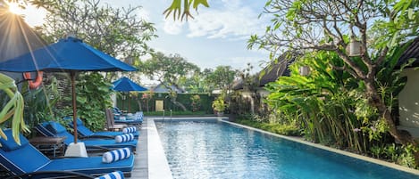 Una piscina al aire libre, sombrillas, sillones reclinables de piscina