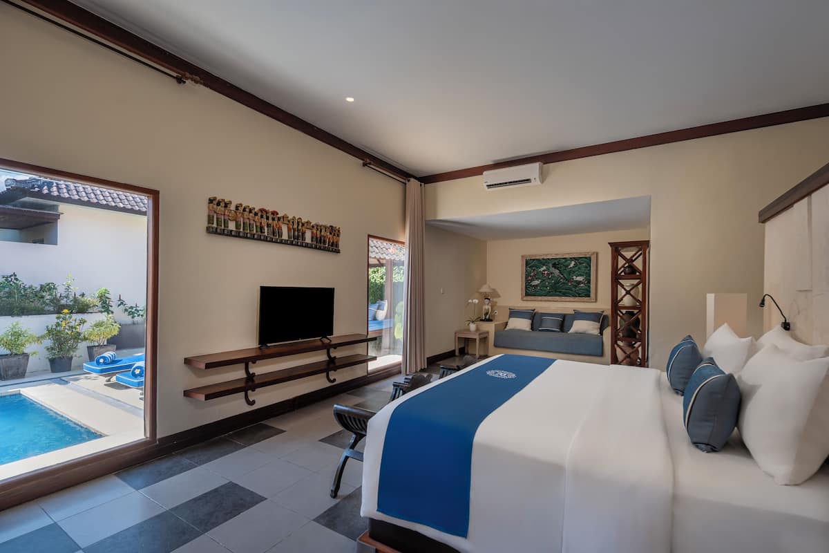 A hotel room with a bed, a desk, a TV, a window, and a view of the outside.