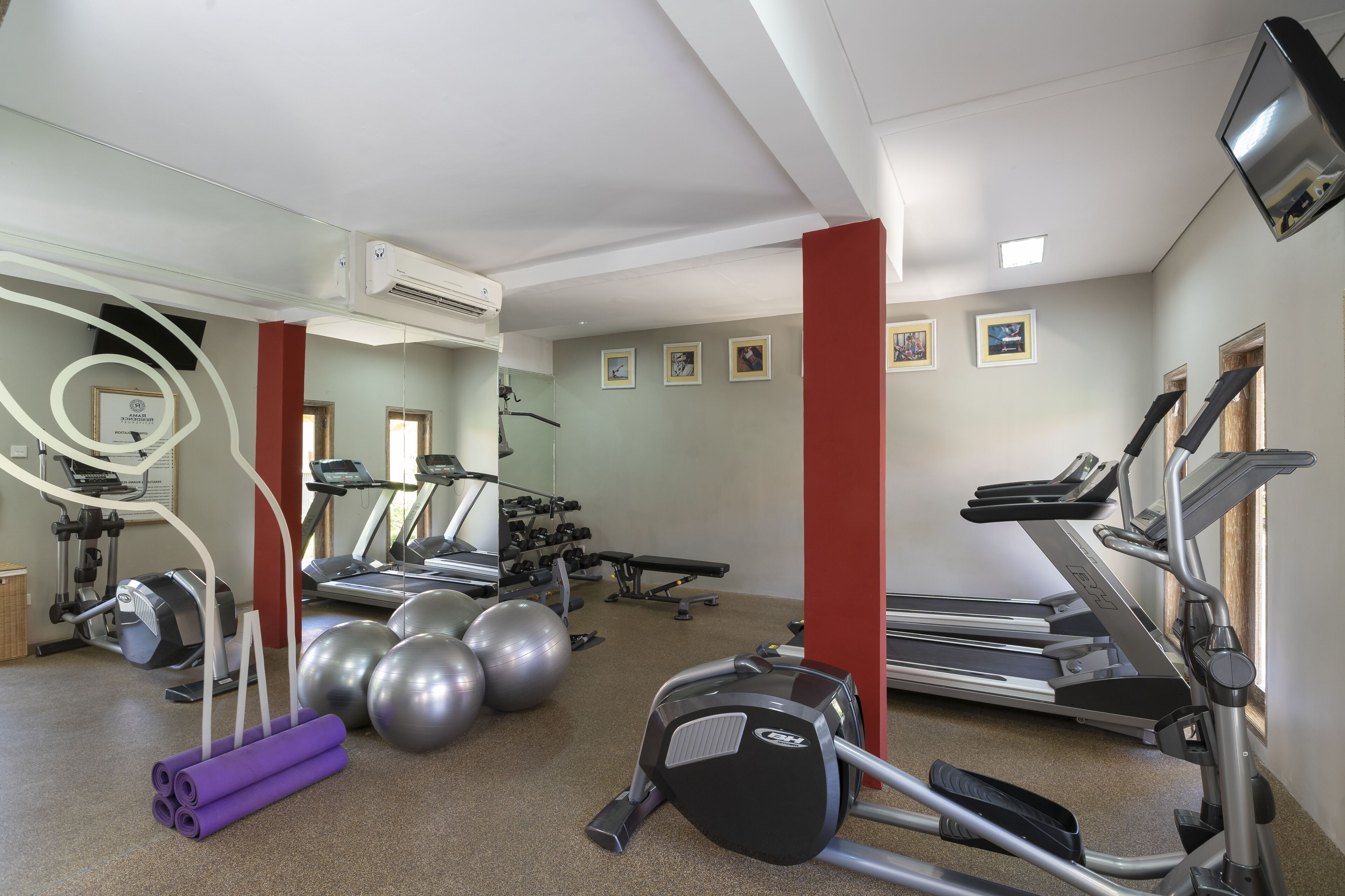 A gym with treadmills, elliptical machines, and exercise balls.