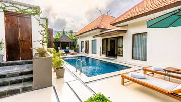 Uma área ao lado da piscina com cadeiras de sol e um gazebo.