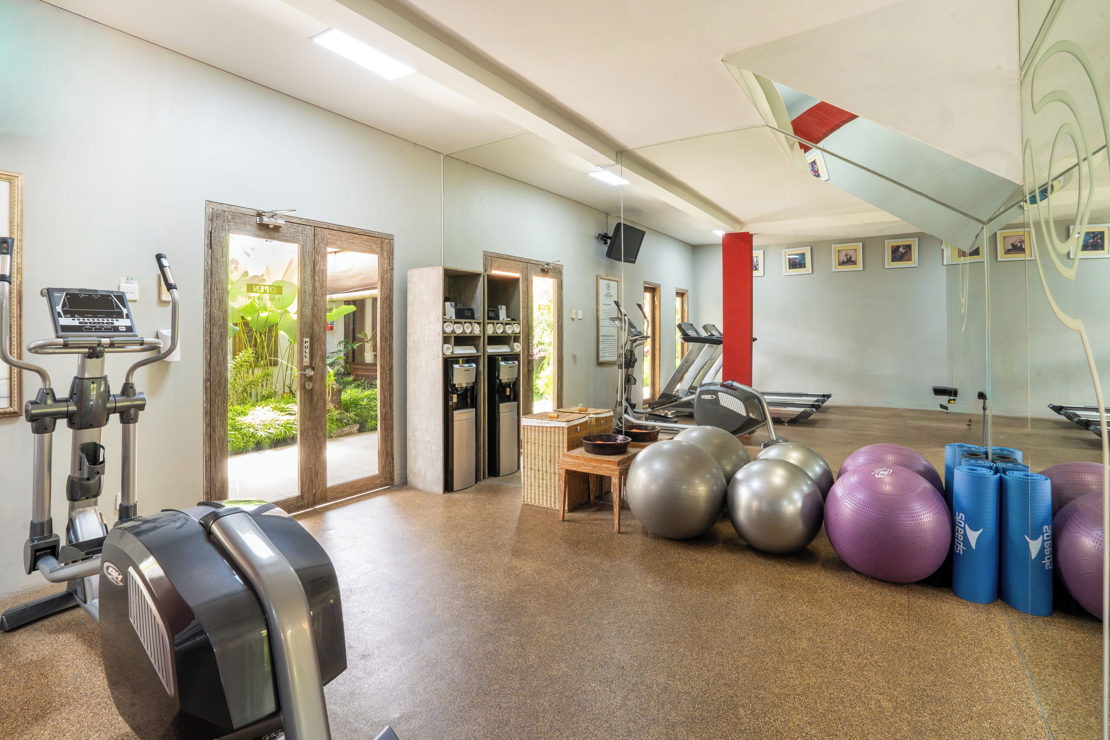 Un gimnasio con equipo de ejercicio, un espejo y pelotas de fitness.