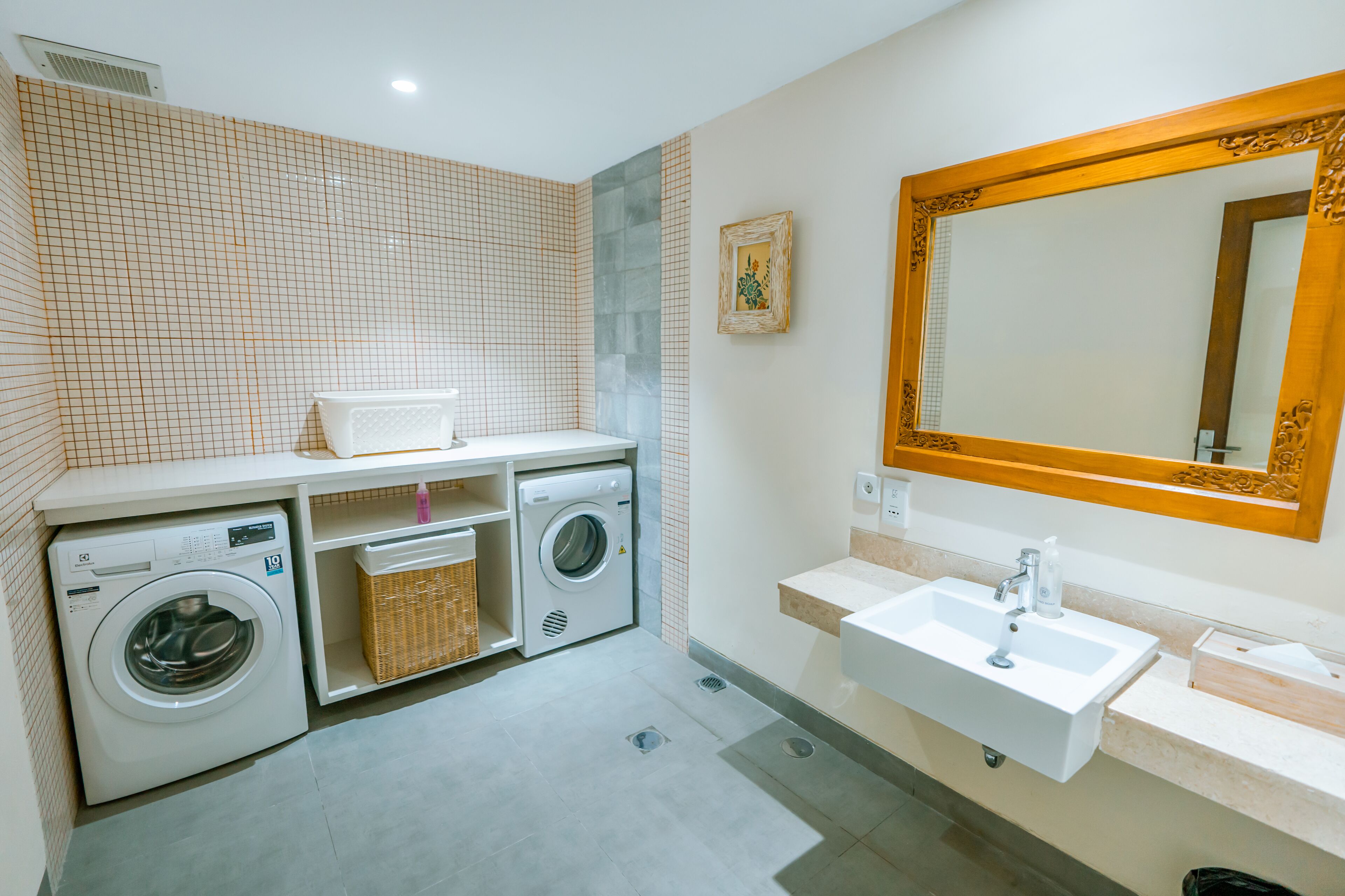 A modern bathroom with a large mirror, a sink, and two washing machines.