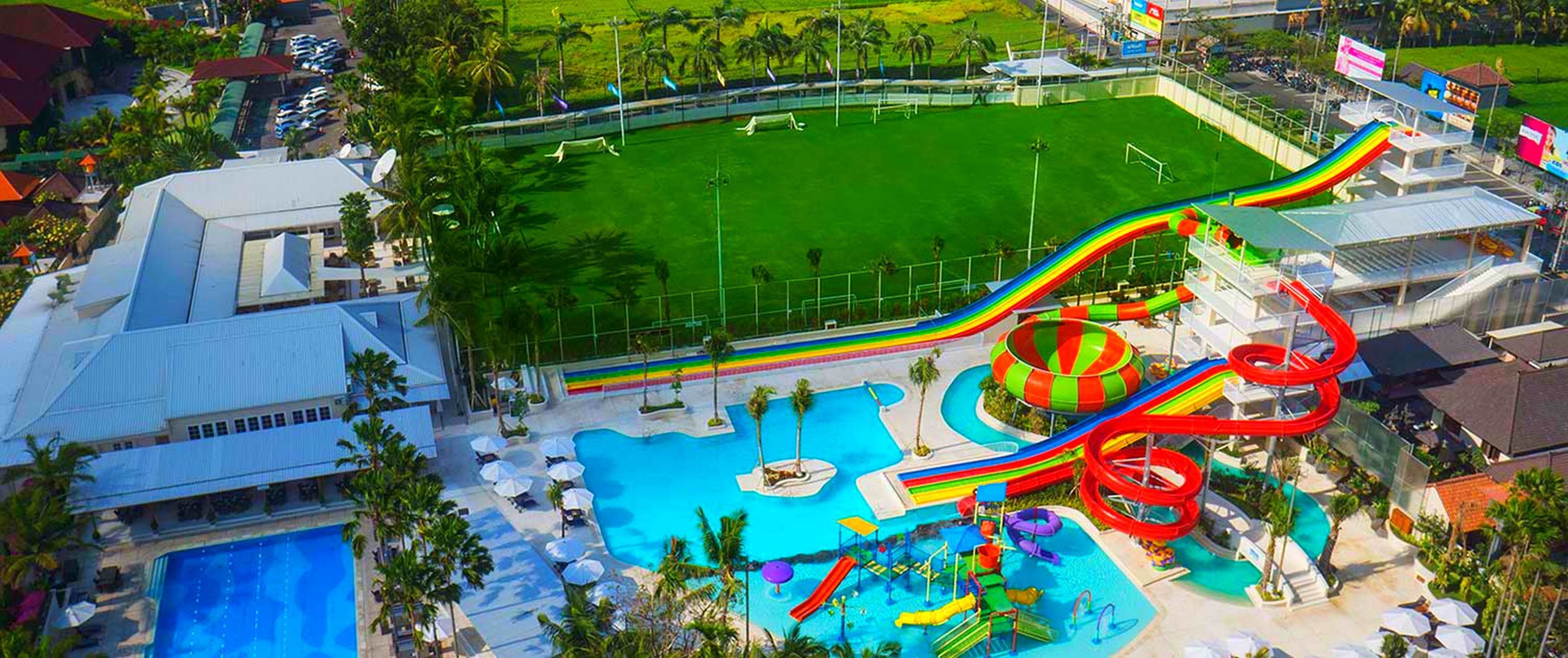 A resort with a large swimming pool, water slides, and a soccer field.